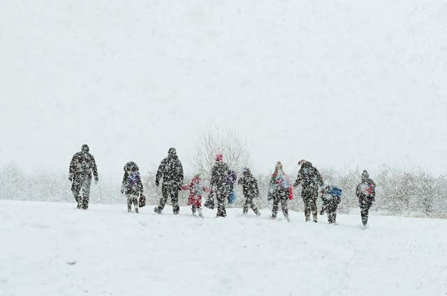 Parents walk their children to school in Ashford, Kent, as heavy snowfall is affecting roads across the UK on Tuesday morning after several centimetres fell in some parts over the night (Gareth Fuller/PA)