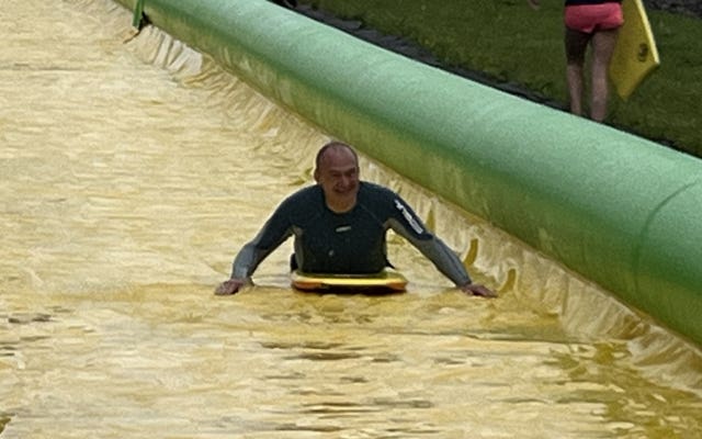 Sir Ed Davey on a yellow water slide
