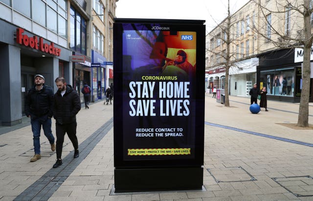 People walk past a ‘Stay Home Save Lives’ sign on Broadmead in Bristol during England’s third national lockdown to curb the spread of coronavirus