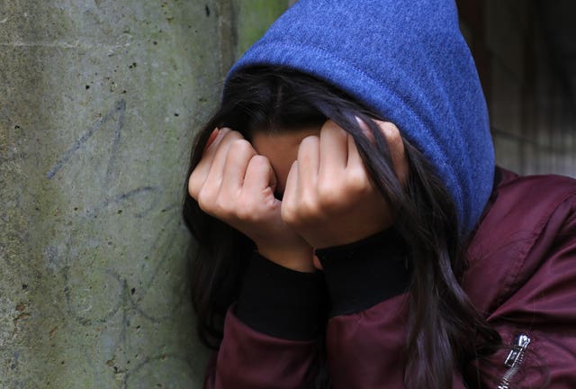 A young person with her hands covering her face