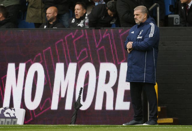 Then-Nottingham Forest manager Ange Postecoglou checks his watch on the touchline in front of an advertising hoarding reading 'No More'