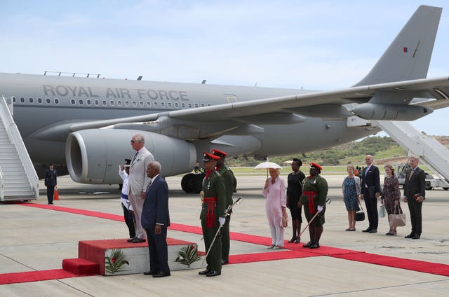 The Prince of Wales (centre left) and the Duchess of Cornwall (centre right) arrive at Argyle International Airport