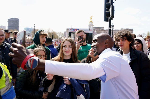 Sir Mo Farah takes photographs with fans in the Buckingham Palace Memorial Gardens ahead of the 2023 London Marathon