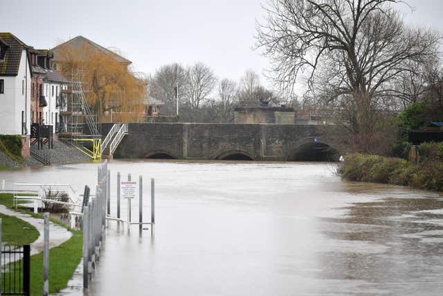 High water flows under a bridge on the River Avon at Tewkesbury (A tractor makes light work of a flooded road near Sutton, Cambridgeshire (Ben Birchall/PA)