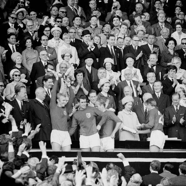 Roger Hunt receives his World Cup winners' medal from the Queen as England captain Bobby Moore holds the trophy aloft 