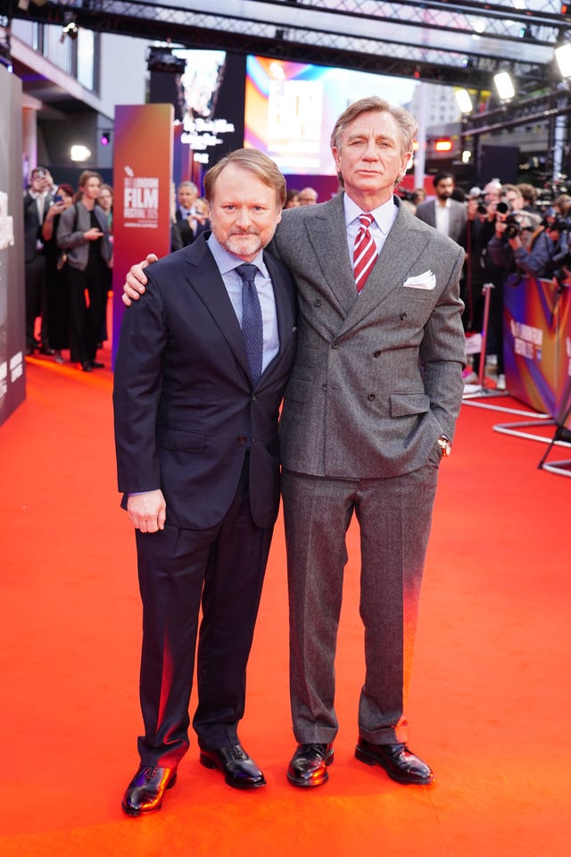 Daniel Craig, right, with his arm around Rian Johnson on a red carpet