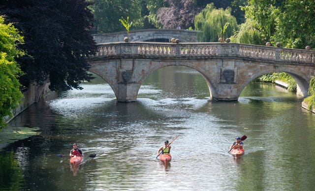 People kayak along the River Cam in Cambridge