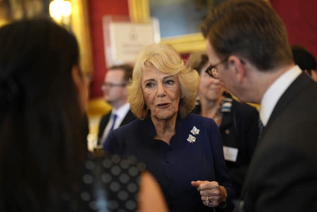 Camilla in discussion with two people who have their backs to the camera