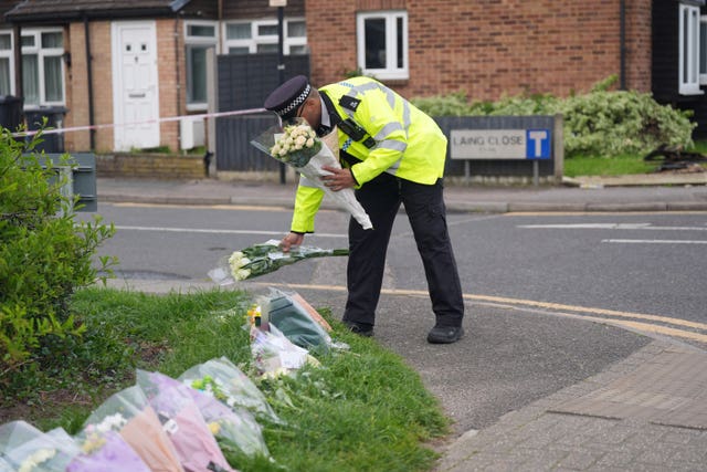A police officer laid flowers on the corner of Laing Close
