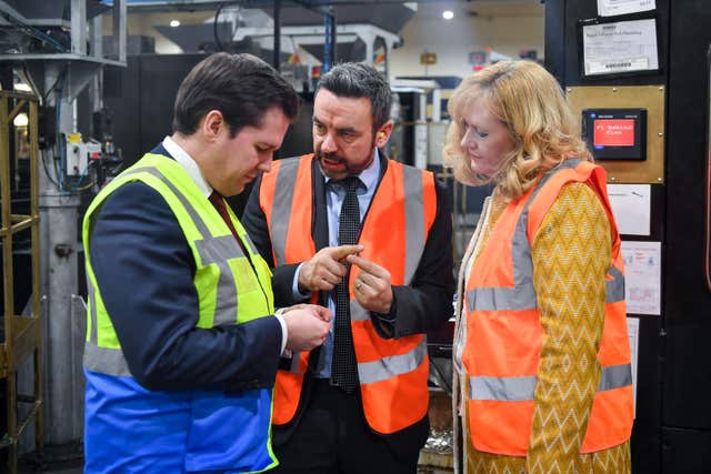 Robert Jenrick, exchequer secretary to the Treasury and Anne Jessopp are shown coins on the production line at the Royal Mint factory in Llantrisant (Ben Birchall/PA)