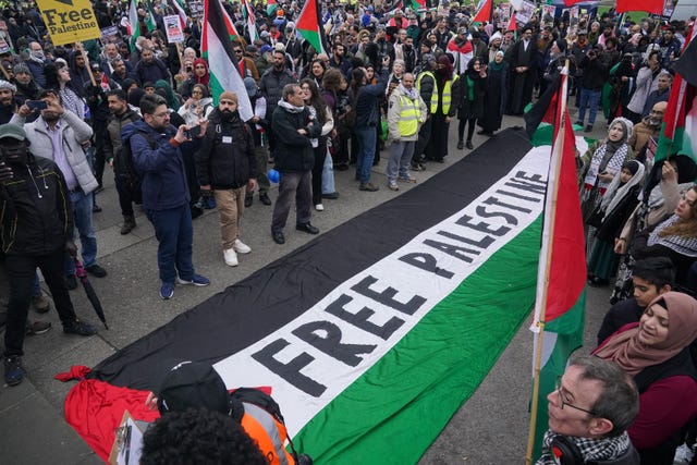 A large Palestine flag with the words 'free Palestine' in the middle of it lays on the ground during a protest