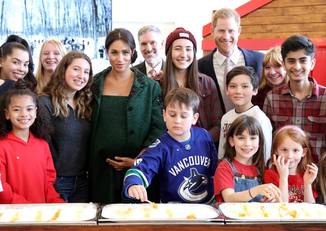 The Duke and Duchess of Sussex pose with children during a visit to Canada House
