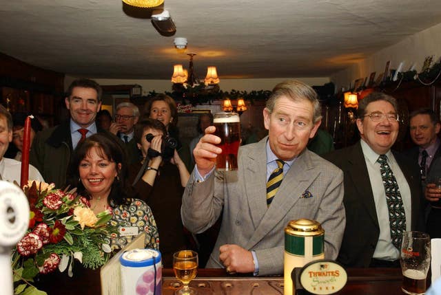 Charles raising a glass as he samples a pint of beer during a visit to the Craven Heifer Hotel in Stainforth near Settle
