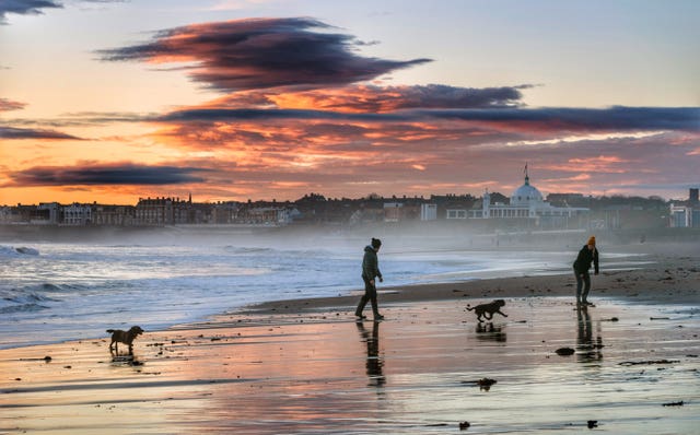 Dog walkers on the beach at sunrise in Whitley Bay, North Tyneside, which was awarded a Blue Flag