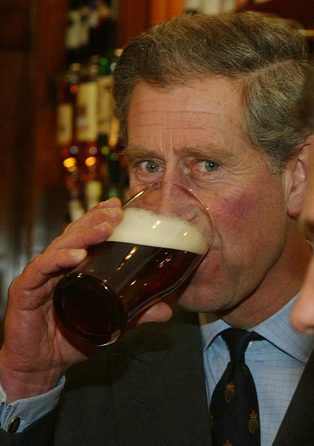Charles sampling a pint of beer during his visit to the village of Poundbury in Dorset