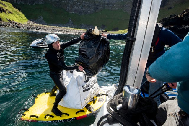 Volunteers load rubbish onto a boat