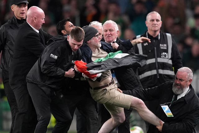 A protester is escorted off the field by security