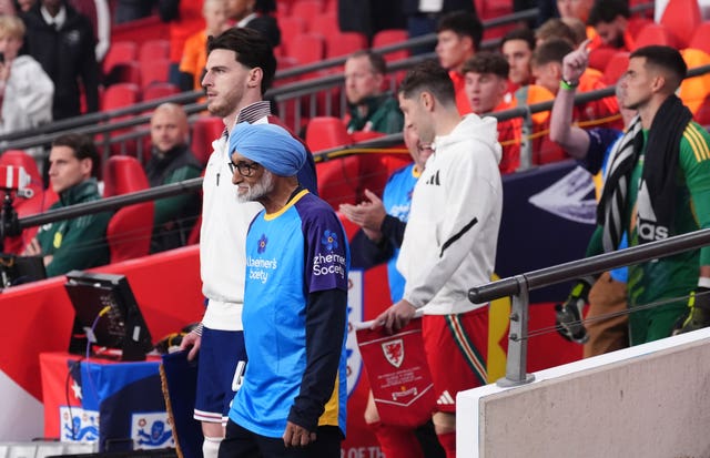 Declan Rice walks out with a mascot representing Alzheimer’s Society as he captained England