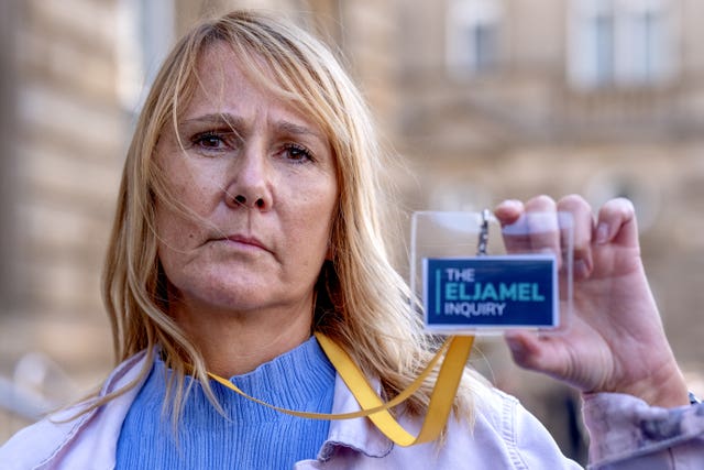 Jules Rose holding up her Eljamel Inquiry pass, standing outside