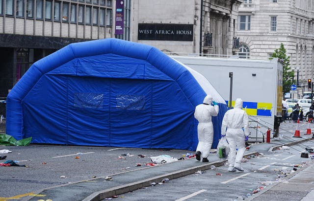 Forensic officers walk past an inflatable field tent at the scene in Water Street near the Liver Building in Liverpool