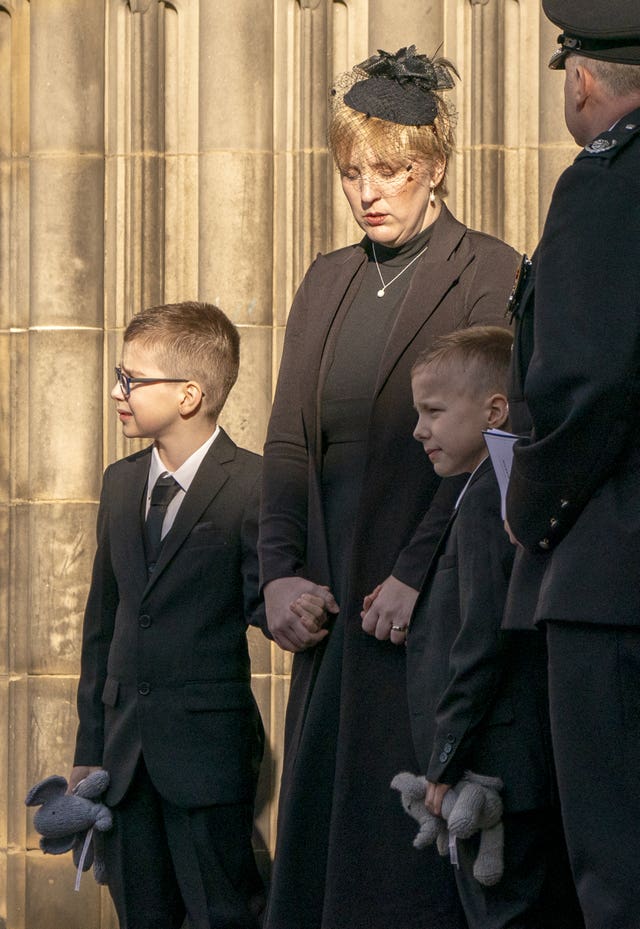 Shelley Martin holding hands with her sons at the funeral of her husband