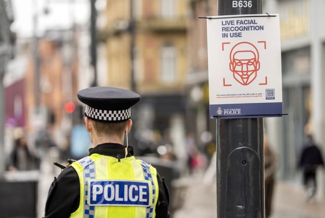 A police officer near a facial recognition in use sign