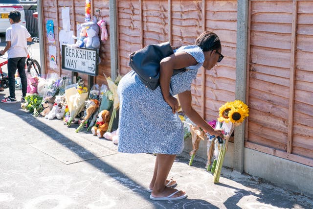 A woman lays flowers near Galpin’s Road in Thornton Heath (Dominic Lipinski/PA)