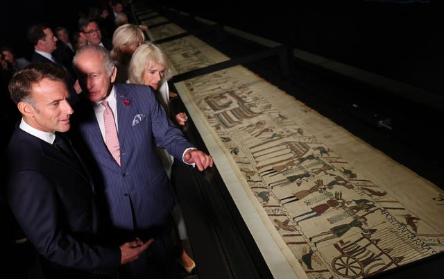 Charles talking to Emmanuel Macron as they look at the Bayeux Tapestry