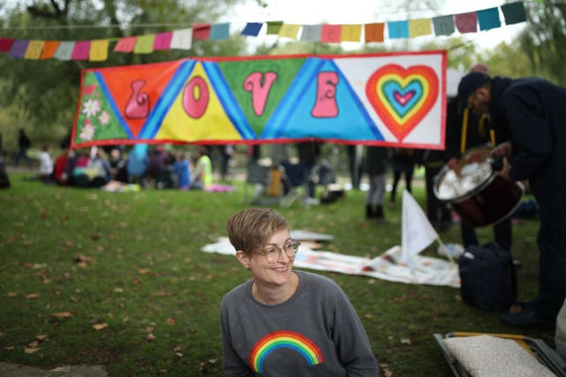 A protester sits beneath a Love banner during an Extinction Rebellion protest in Westminster, London