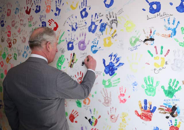 he Prince signs his hand print he created on a prior visit in 2001 (Aaron Chown/PA)