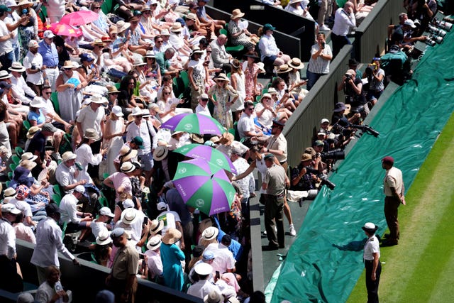 Aryna Sabalenka passes over a bottle of water to stewards, who are attending to a spectator struggling with the hot conditions on Centre Court