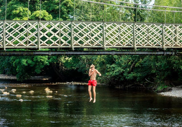 A person jumps from a bridge into the River Wharfe near Ilkley in Yorkshire (Danny Lawson/PA)