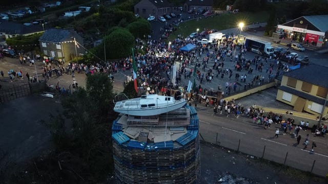 People watch as the pyre with a boat on top is lit