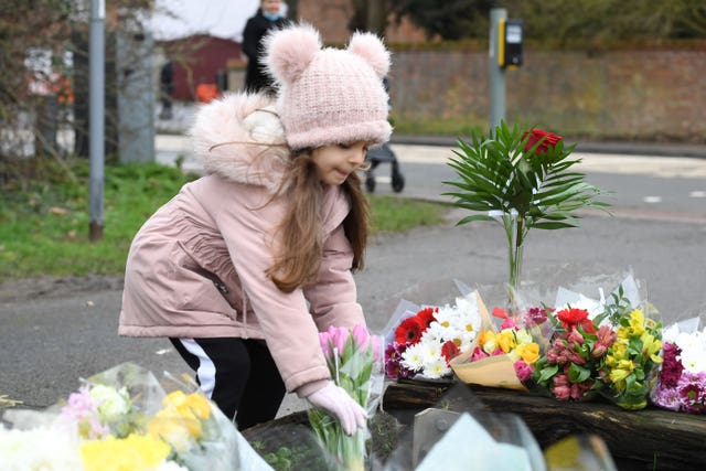 A girl leaves flowers for Captain Sir Tom Moore