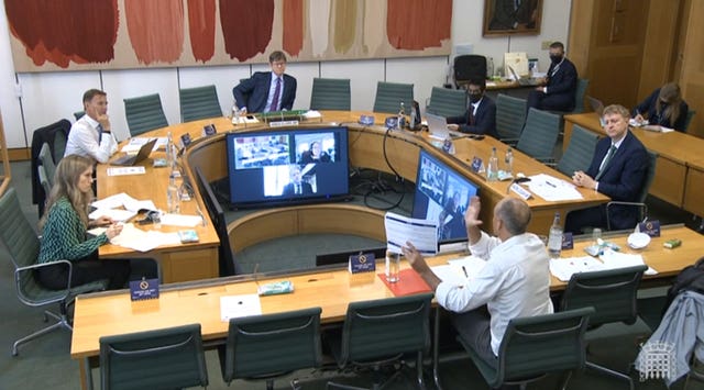 Dominic Cummings, former chief adviser to Prime Minister Boris Johnson, holds up a document while giving evidence to a joint inquiry of the Commons health and social care and science and technology committees