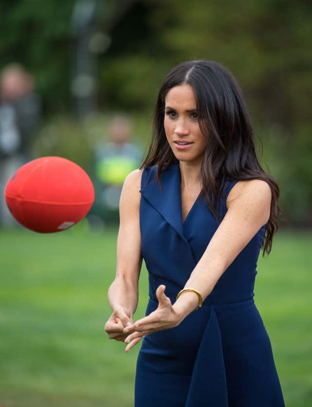 The Duchess of Sussex handballs an Australian rules football