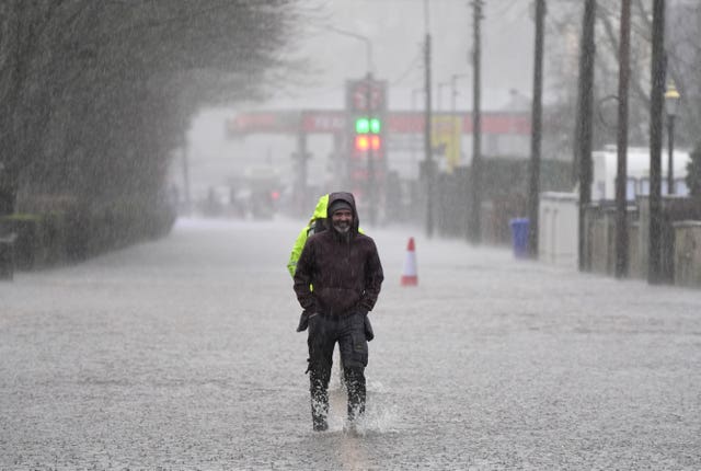 A man standing in the rain with flood water up to his shins