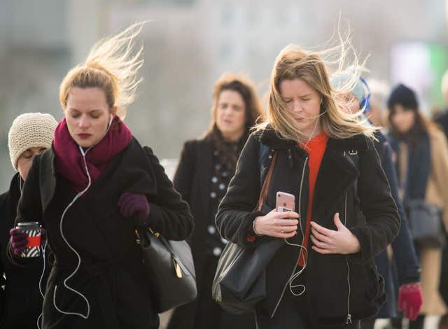 People in winter coats and scarves cross Waterloo Bridge in central London (Dominic Lipinski/PA)