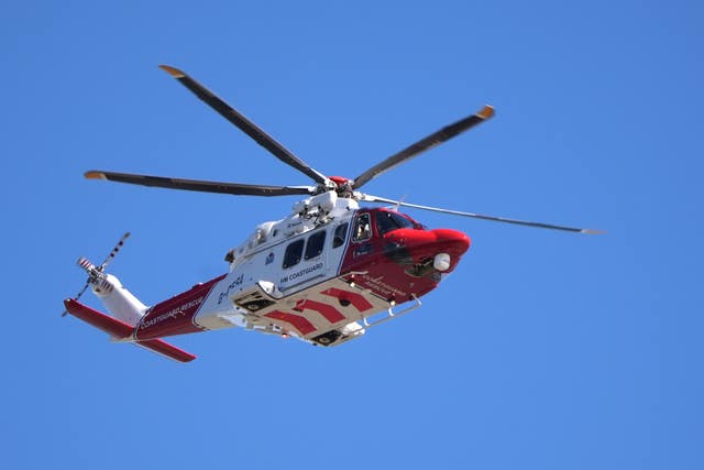 A Coastguard helicopter in flight, against blue skies