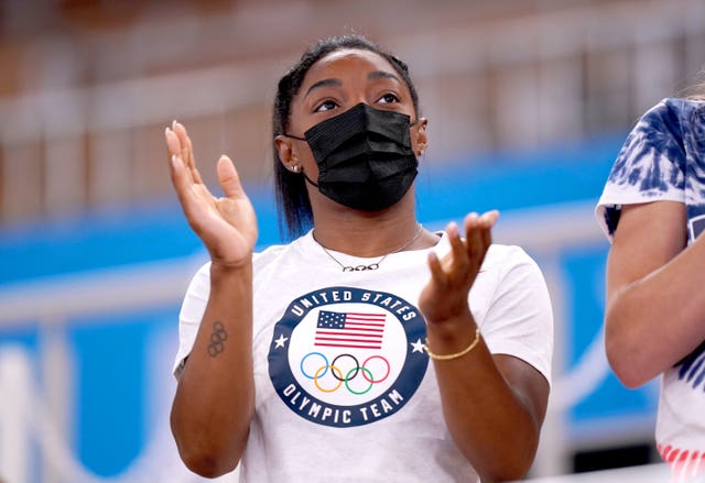 Simone Biles claps in the stands