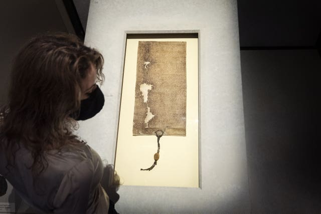 A staff member at the British Museum in London looks at a piece of the Magna Carta (1225)