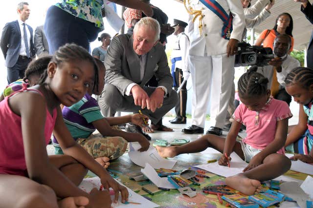 The King crouching down as he speaks to children