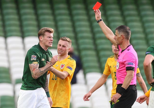 Referee Anastasios Sidiropoulos shows a red card to Ireland's James McClean