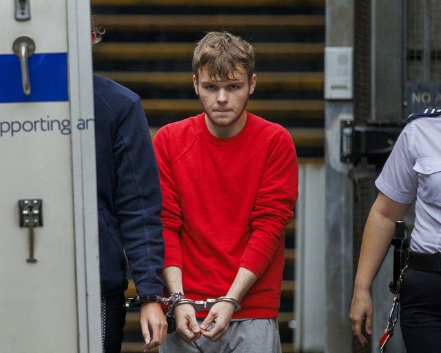 A handcuffed man wearing a red jumper