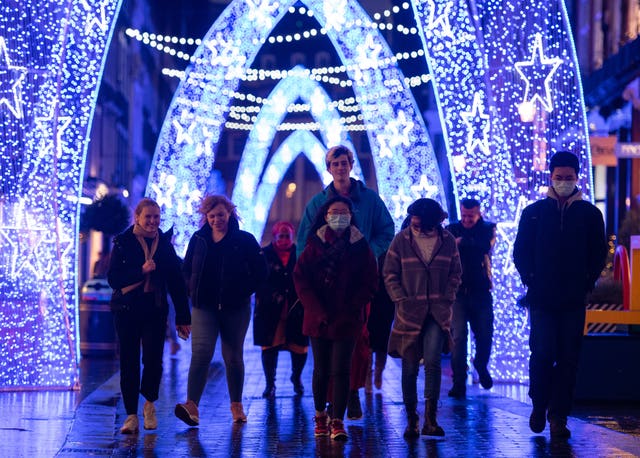 Shoppers walk through Christmas lights on South Molton Street, in central London