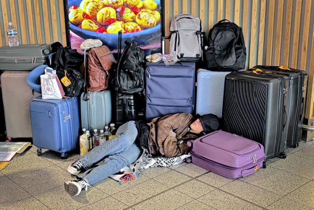 A passenger sleeping on the floor surrounded by luggage at Gatwick Airport