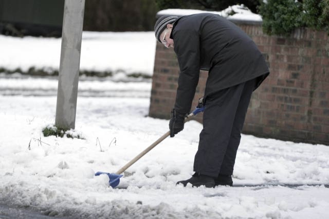 A man clears snow from the pavement in Woolton, Liverpool