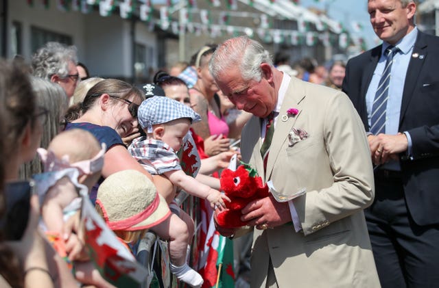 The Prince of Wales, who was given a toy dragon from a member of the public, gives it to a child to play with as he arrives for a visit to White Rose Primary School in Elliots Town, New Tredegar, in south Wales. Andrew Matthews/PA