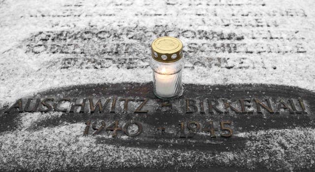 A candle on a memorial plaque at the end of the railway tracks at Birkenau to mark International Holocaust Memorial Day (Dave Thompson/PA)