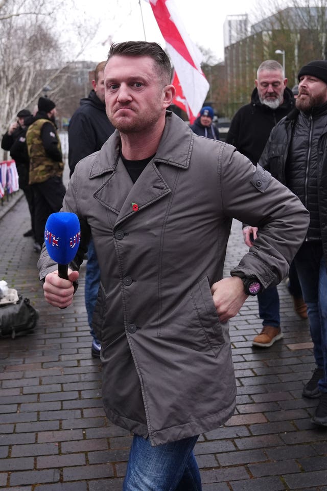 Tommy Robinson standing outside, holding a microphone